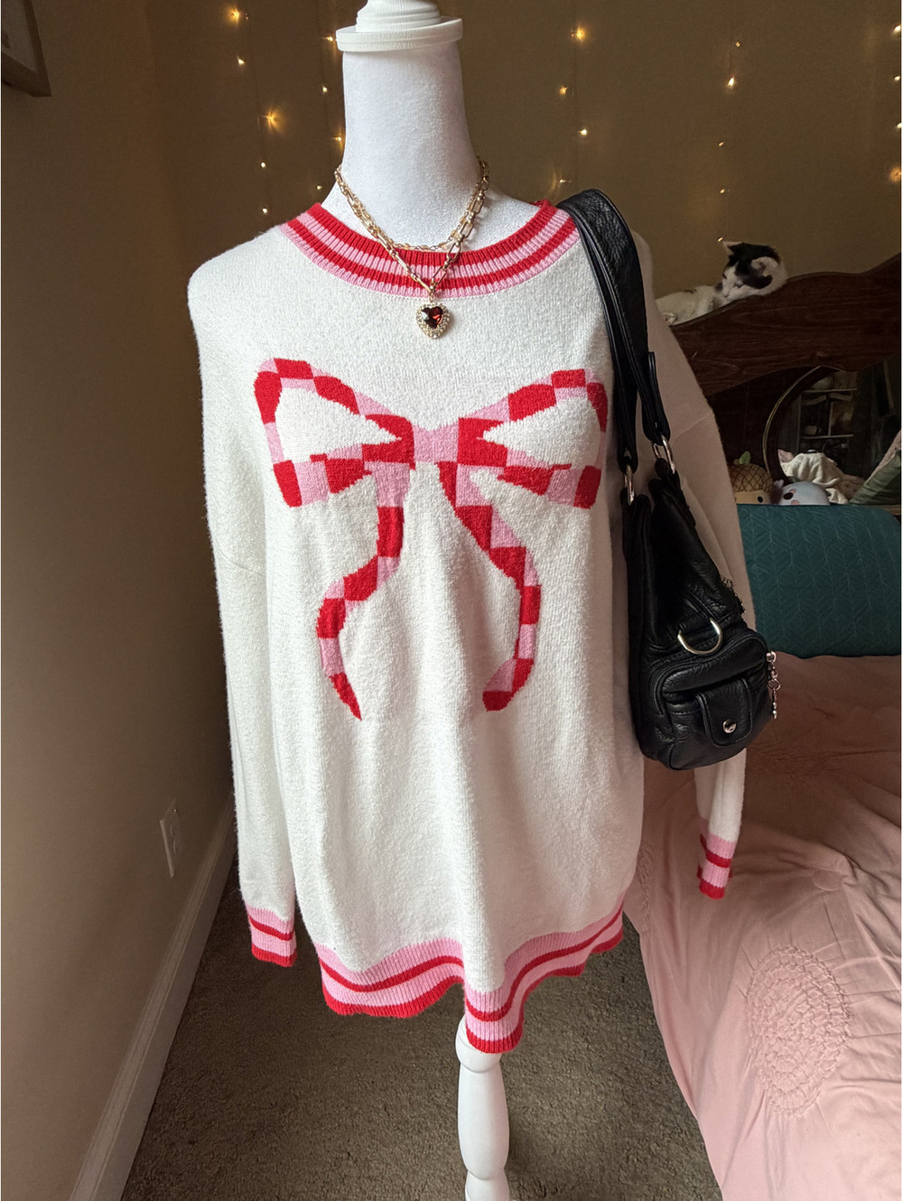 This cream pullover features a stunning bold pink and red checkered bow/ribbon